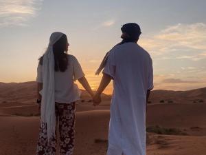 梅尔祖卡Services Luxury Camp的站在沙漠中的男人和女人握手