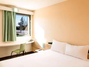 埃武拉埃武拉宜必思酒店的一间卧室设有一张床、一个窗口和一把椅子