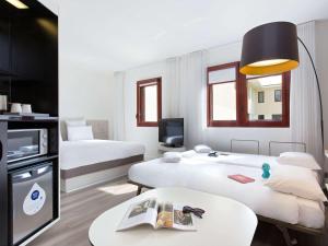 佩皮尼昂Novotel Suites Perpignan Centre的酒店客房设有两张床和一张桌子。