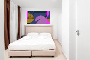 圣凯撒利亚温泉19 Summer Suites的卧室配有一张白色床,墙上挂有绘画作品