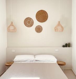 莱乌卡Camere Assúd的卧室配有一张白色床,墙上有篮子