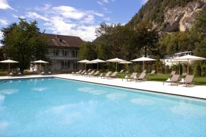 因特拉肯维多利亚少女峰温泉大酒店的一个带椅子和遮阳伞的大型游泳池