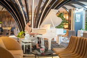 头顿Premier Pearl Hotel Vung Tau的坐在大堂的白钢琴上的女人
