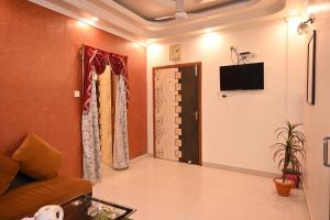 MāldahHOTEL GITANJALI的客厅配有沙发和墙上的电视