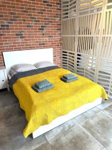 罗兹Apartament Łodzianka的一张黄色毯子和砖墙床