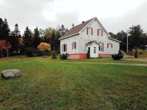 圣安娜德蒙Chill Shack - Auberge Jeunesse的草场上红色修剪的白色房子