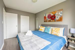 汉密尔顿Newly Renovated 2BR Unit in Glenview West的一间卧室配有一张带蓝色床单和绘画的床。