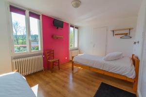 MontcuqHôtel La Barguelonne的一间卧室配有一张床和粉红色的墙壁