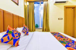 乌代浦FabExpress Mewar Shine的一间卧室配有一张带色彩缤纷枕头的床和窗户。