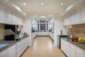 德斯坦圣丹斯汀格兰德大道住宿酒店的一间设有白色橱柜和瓷砖地板的大厨房