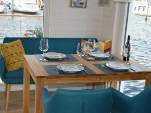 艾恩松Houseboat Hecht in Egernsund at the Marina Minde的一张木桌,上面放有酒杯和盘子