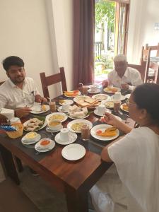 阿努拉德普勒Blooming Holiday Resort的一群坐在餐桌上吃食物的人