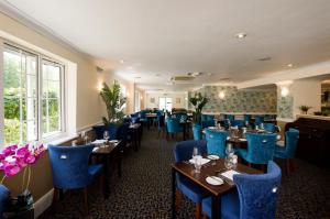 胡克贝辛斯托克Spa酒店的一间在房间内配有蓝色椅子和桌子的餐厅