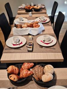 La GleizeLes chambres de la Vaulx-Renard的一张长桌,盘子里放着羊角面包和糕点