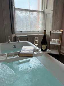 奥赫里姆Clone Country House的浴缸配有一瓶葡萄酒和玻璃