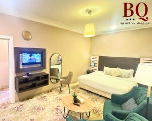 布赖代البندقية للخدمات الفندقية BQ HOTEL SUITES的一间卧室配有一张床、一台电视和一张沙发