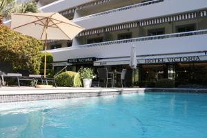 戛纳维多利亚酒店的一个带遮阳伞的游泳池以及酒店