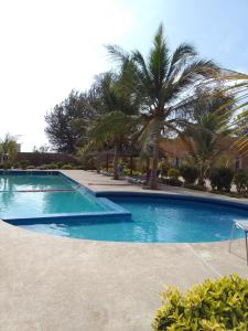 达喀尔Hôtel Entre Lac et Mer的一座棕榈树环绕的大型游泳池