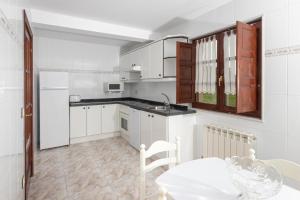 纳韦斯Apartamentos el Acebo的厨房配有白色橱柜、桌子和水槽。