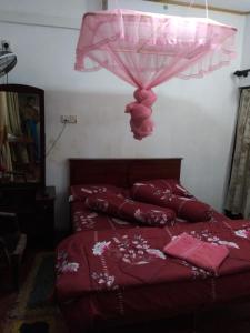 瓦都瓦Suriya Ocean Villa的一间卧室配有红色的床和粉红色的雨伞