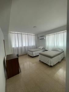 巴拿马城Habitaciones privadas en un departamento encantador的一间卧室配有两张床、一张书桌和窗帘