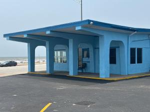 加尔维斯敦Econo Lodge Galveston Seawall的海滩旁的蓝色建筑,有车