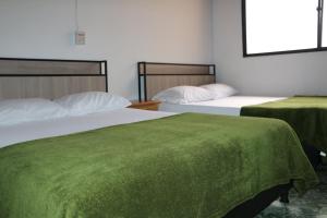 麦德林Aparta Suite Torre De Prado Penthouse的配有绿床单的客房内的两张床