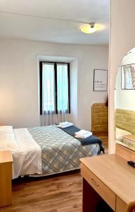 加尔达湖滨瓦拉内酒店的一间卧室配有一张床、一张书桌和一面镜子