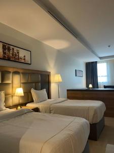利雅德بياسة للاجنحة الفندقية的酒店客房设有两张床和窗户。