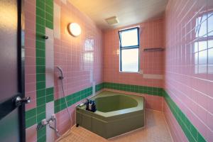 成田Grand Hotel Narita Airport - Vacation STAY 56496v的浴室铺有粉色和绿色瓷砖,配有浴缸。