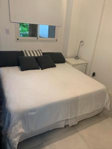 布宜诺斯艾利斯Eugene City的卧室内的一张带黑色枕头的白色床