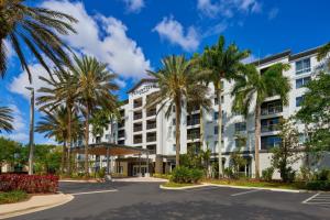 韦斯顿Courtyard by Marriott Fort Lauderdale Weston的街道前方有棕榈树的建筑