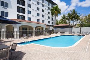 韦斯顿Courtyard by Marriott Fort Lauderdale Weston的酒店前方设有桌椅的游泳池