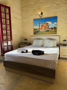 Għajn il-KbiraThe Nest 148 Townhouse的卧室配有一张大床,墙上挂有绘画作品