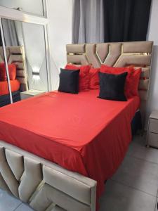 圣地亚哥洛斯卡巴Aparta estudio en santiago #1的一张大床,配有红色床单和黑色枕头
