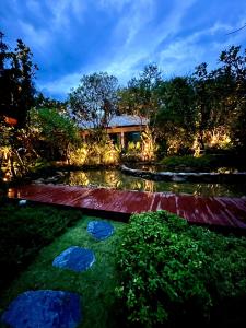 卡农Luxtalay khanom Hotel的夜晚在院子里有池塘的房子