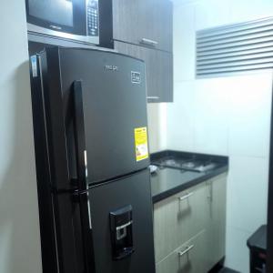 马尼萨莱斯LA CASA DEL CABLE -Atractivo Único Sector Cable 104-的厨房配有黑色冰箱,配有微波炉