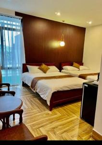 Ap Rạch SoiKhách Sạn Phụng Vy的酒店客房设有两张床和一张桌子。