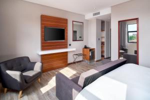 比勒陀利亚Protea Hotel by Marriott Pretoria Hatfield的酒店客房配有床、沙发和电视。