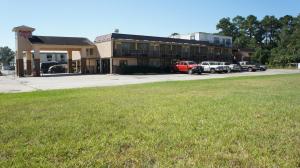 橙县Executive Inn & Suites的一座有汽车停在草地前面的建筑