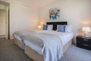 凯恩斯325 Harbour Lights with Garden View的卧室配有带蓝色枕头的大型白色床