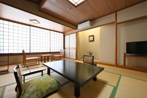 草津Osakaya Ryokan的客厅配有桌椅和电视。