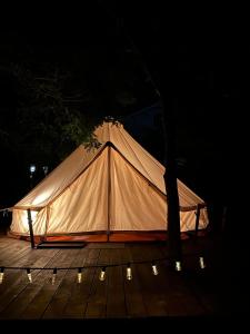 西斯纳迪奥拉Glamping Cisnadioara的夜间木制甲板上的白色帐篷