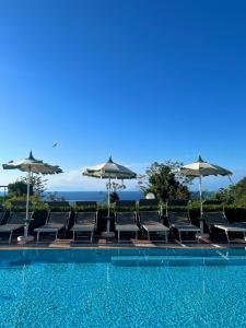 伊斯基亚Resort Villa Flavio的一个带椅子和遮阳伞的游泳池