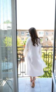 利沃夫Nota Bene Hotel & Restaurant的穿着白色衣服的女人,从窗户望出去