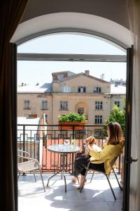 利沃夫Nota Bene Hotel & Restaurant的坐在椅子上和孩子坐在阳台上的女人