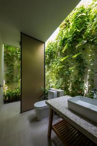 富国Villa Wyndham Phu Quoc的一间带两个卫生间和植物墙的浴室