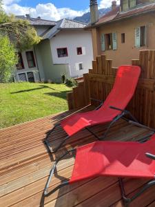 圣热尔韦莱班Appartement Saint-Gervais-Les-Bains的木制甲板上的一个红色椅子