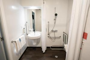 马德里Travelodge Madrid Metropolitano的白色的浴室设有水槽和淋浴。