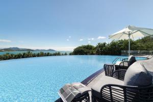 三亚三亚君吉海景酒店的一个带椅子和遮阳伞的大型游泳池